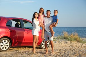 A happy family takes a road trip to the beach after learning when to refinance their car loan.
